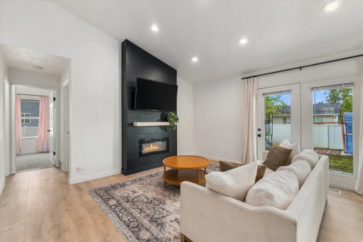 Vaulted ceiling, recessed lighting, wood-finish flooring, built-in fireplace, and double glass panel doors