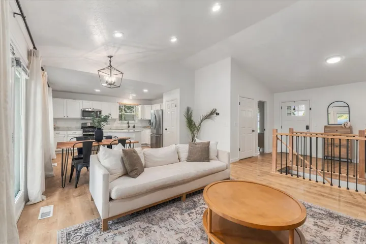 Open-concept living space featuring wood-finish flooring, recessed lighting, and a vaulted ceiling
