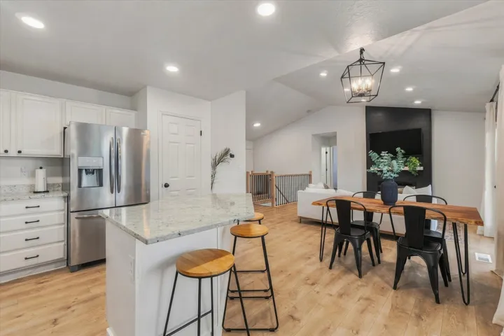 Kitchen featuring white cabinetry, stainless steel refrigerator, and a granite-style island