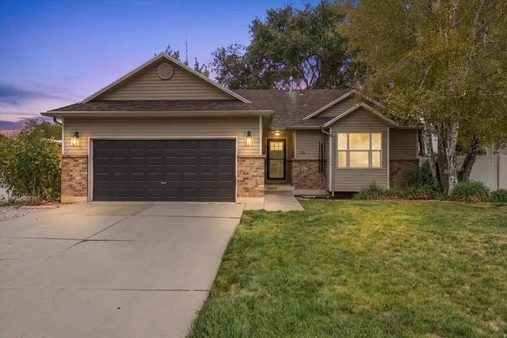Exterior featuring horizontal siding, brick accents, an attached two-car garage, a concrete driveway, and a manicured lawn