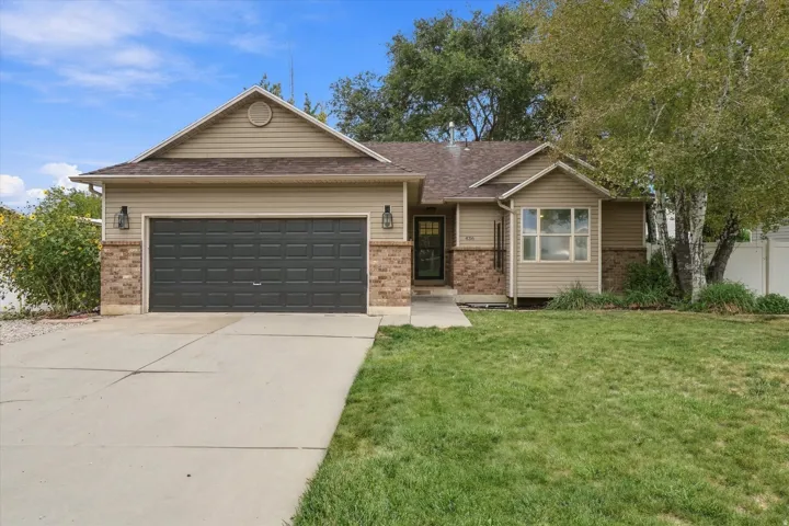 Single-story residence featuring a two-car garage, brick and siding exterior, front lawn, and a paved driveway