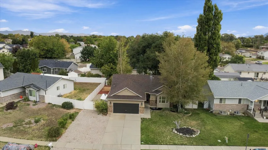 Single-story residence featuring a two-car garage, mature landscaping, and a paved driveway
