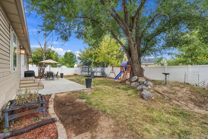 Spacious backyard featuring a concrete patio, wood-finish deck, mature tree, and privacy fencing