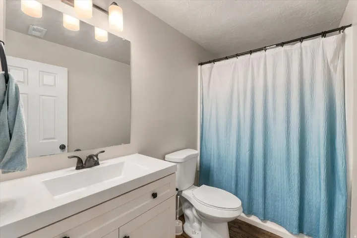 Integrated vanity with a rectangular sink, bronze-finish faucet, and overhead bar lighting