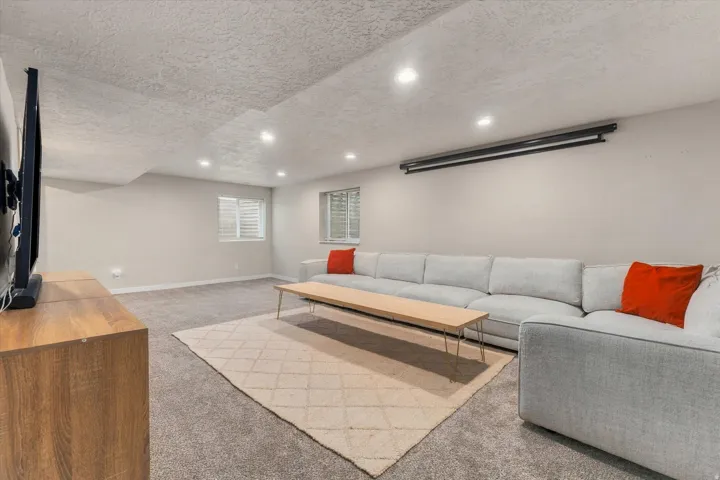 Recessed lighting illuminates this carpeted space featuring a projection screen, windows with blinds, and light-colored walls