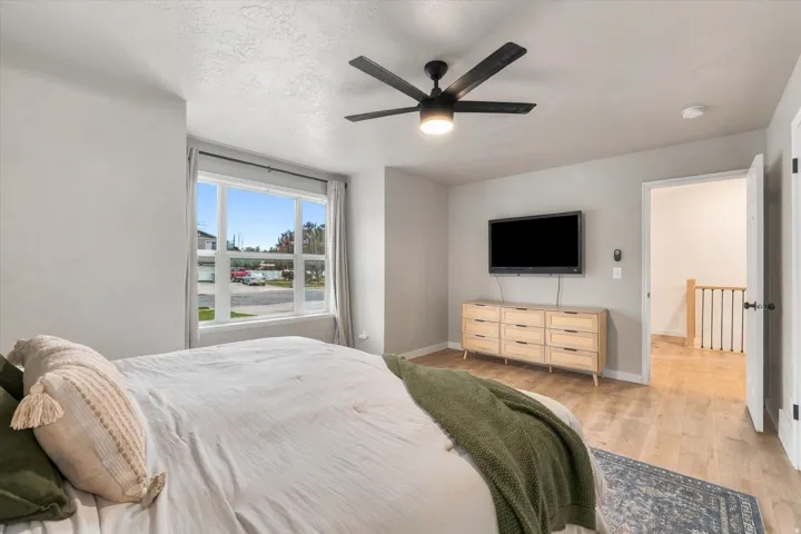 Wood-finish flooring with light wall tones and a ceiling fan with integrated lighting