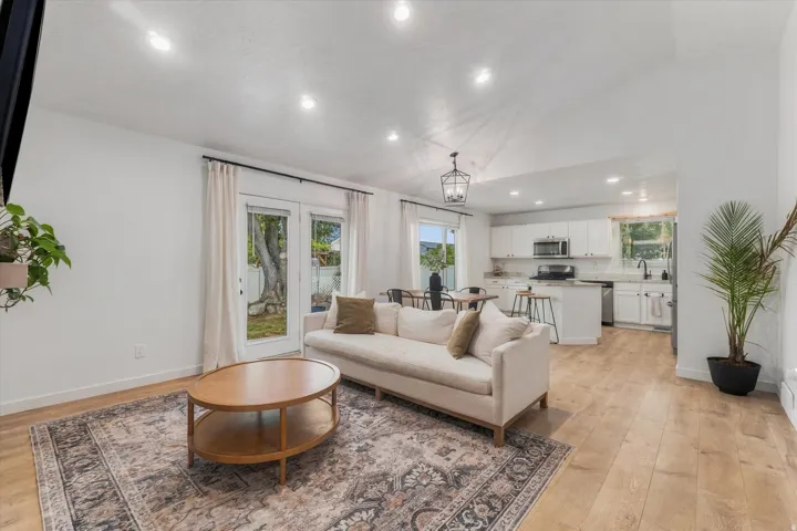 Open-concept living area with wood-finish flooring, recessed lighting, and a vaulted ceiling