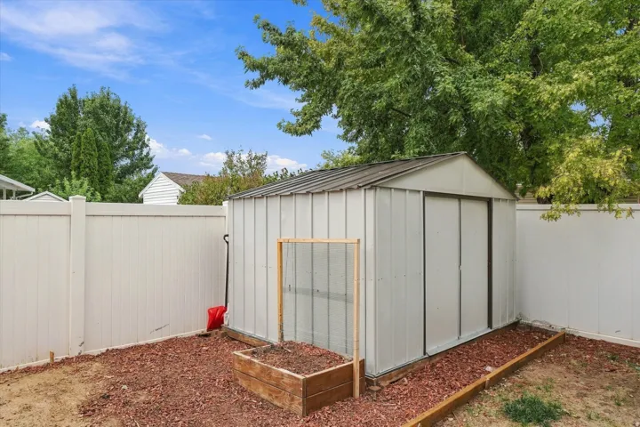 Private backyard featuring a utility shed and raised garden bed
