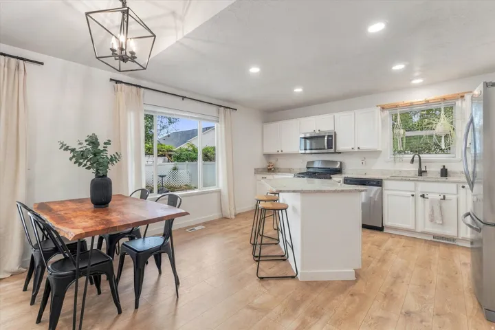 Open-concept kitchen and dining area featuring light wood-finish flooring, white cabinetry, a central island with countertop, and recessed lighting