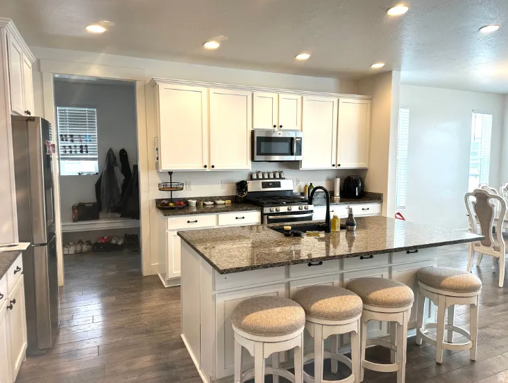 Kitchen featuring white cabinetry, stainless steel appliances, recessed lighting, and an island with a stone-finish countertop