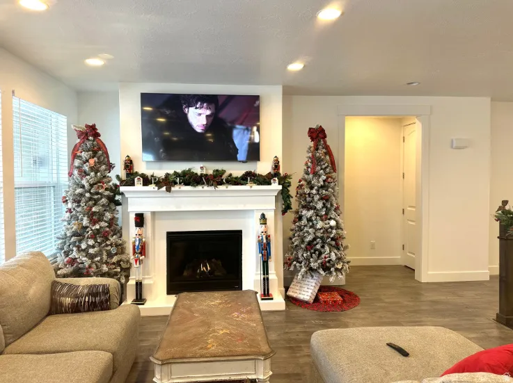 Christmas time. White fireplace with a dark insert, recessed lighting, and wood-finish flooring