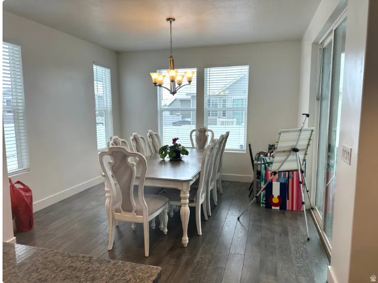 Hardwood-finish flooring, multiple windows with blinds, sliding glass door, overhead chandelier
