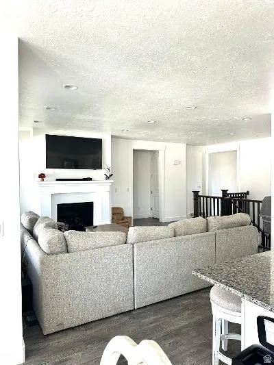 White-painted fireplace surround with mantel, recessed ceiling lighting, wood-finish flooring, and a stone-finish countertop