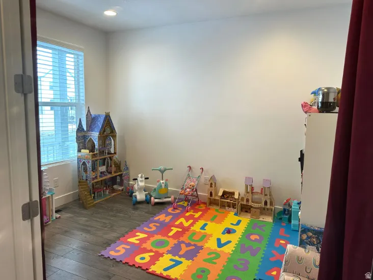 Den. Recessed lighting illuminates wood-finish flooring and neutral wall tones