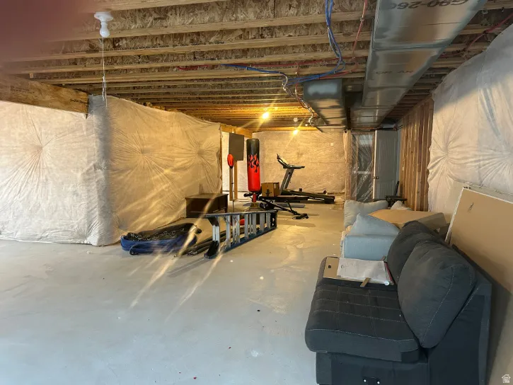 Unfinished basement space with concrete flooring, exposed ceiling joists, and visible insulation