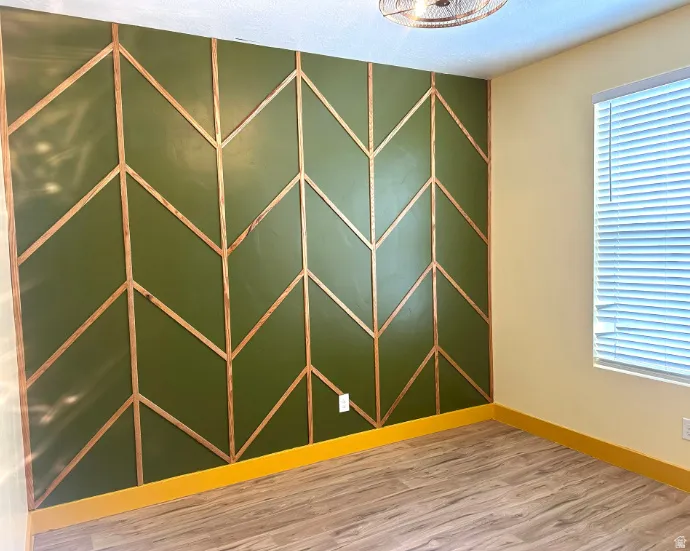 Accent wall with a chevron wood panel design, wood-finish flooring, and a ceiling-mounted light fixture