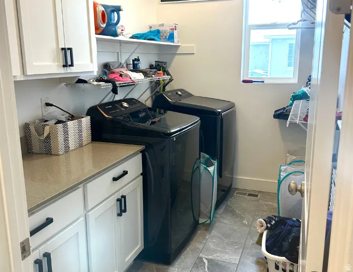 Laundry area featuring a window, overhead shelving, white cabinetry with dark hardware, and a light-toned countertop