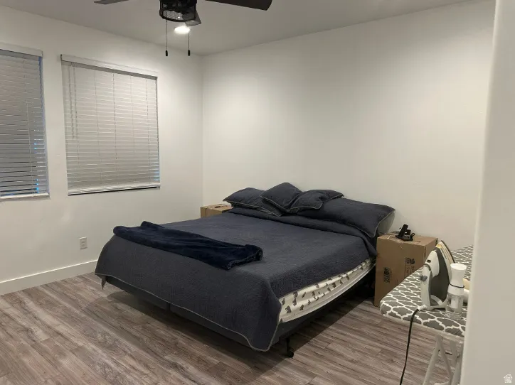 Wood-finish flooring, white walls, and a ceiling fan with integrated lighting