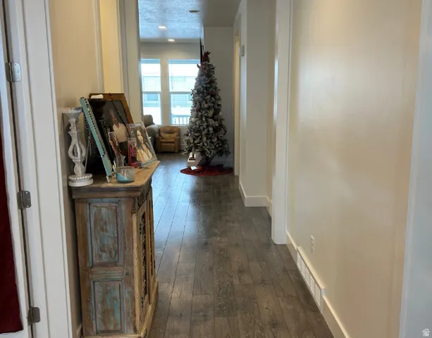 Wood-finish flooring extending through the hallway into a bright living area, featuring recessed lighting, and large windows