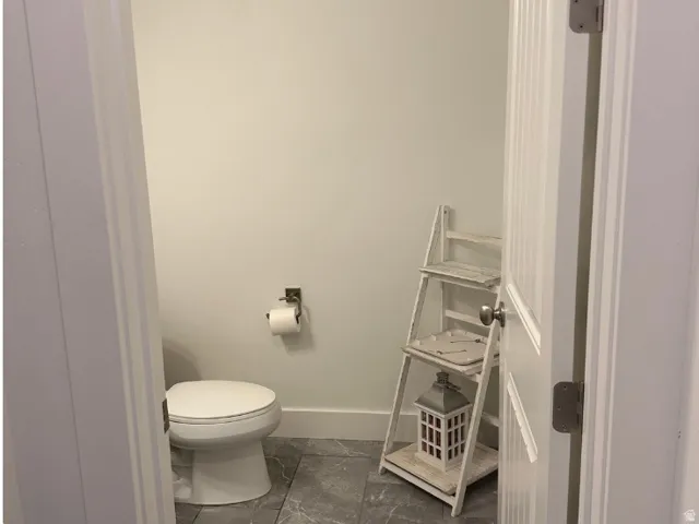 White toilet with a round bowl and a polished chrome toilet paper holder