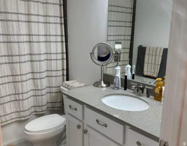 White vanity with cabinet storage, integrated oval sink, and a speckled countertop