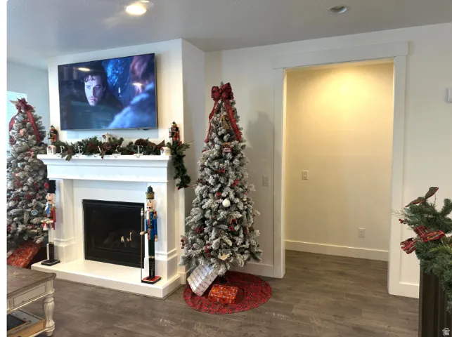 Christmas time. White mantel with a black hearth, wood-finish flooring, and a cased opening