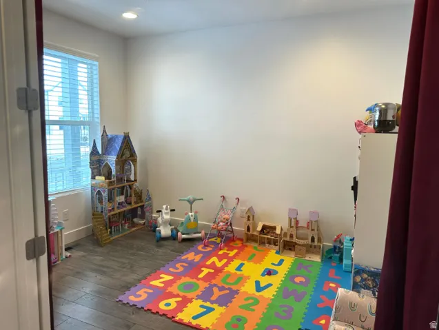 Den. Recessed lighting illuminates wood-finish flooring and neutral wall tones