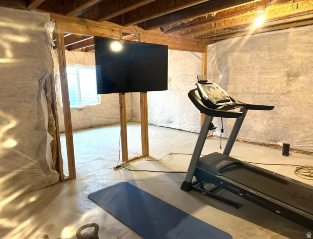 Unfinished basement space with exposed wooden ceiling joists and framed wall sections