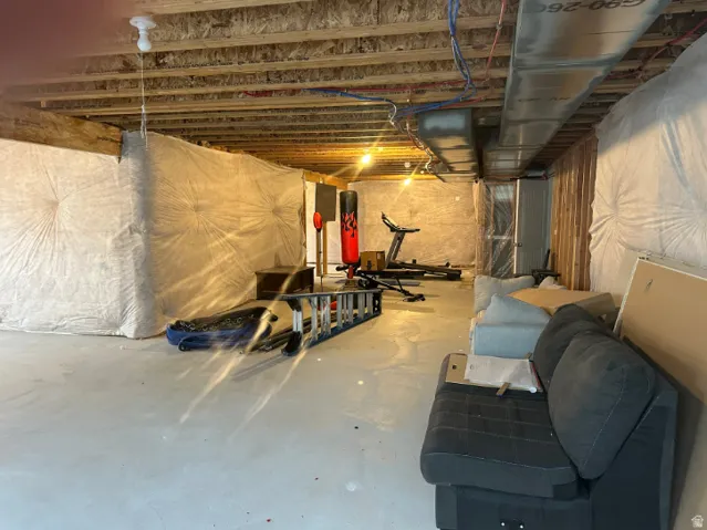 Unfinished basement space with concrete flooring, exposed ceiling joists, and visible insulation