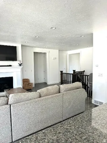 Recessed lighting, white trim, wood-finish flooring, and a dark wood staircase railing