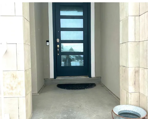 Modern entry door with five frosted glass panels, surrounded by stucco and large format stacked stone columns