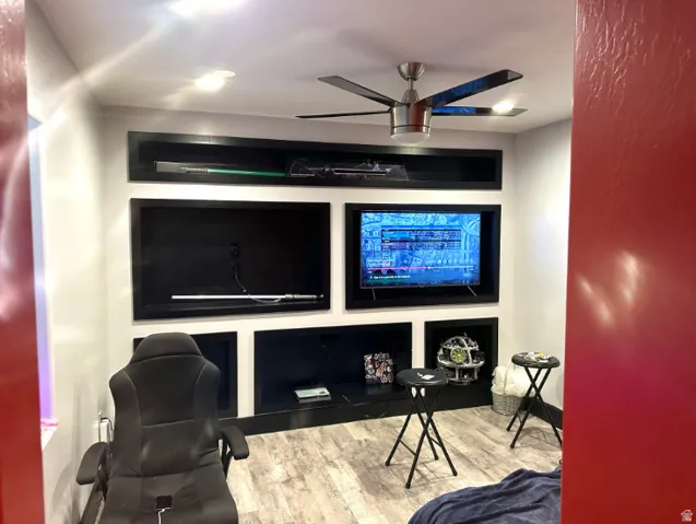 Built-in media center game room with shelving, recessed lighting, ceiling fan, and wood-finish flooring