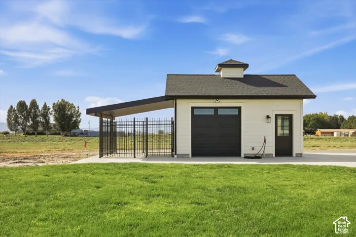 Detached structure featuring a cupola, dark shingle roof, white horizontal siding, and an attached covered area with black metal fencing