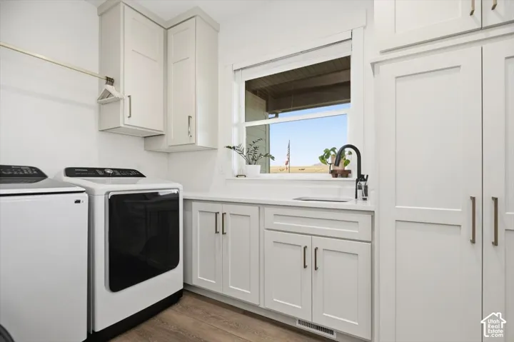 Light-toned cabinetry, wood-finish flooring, undermount sink, black gooseneck faucet, and a large window