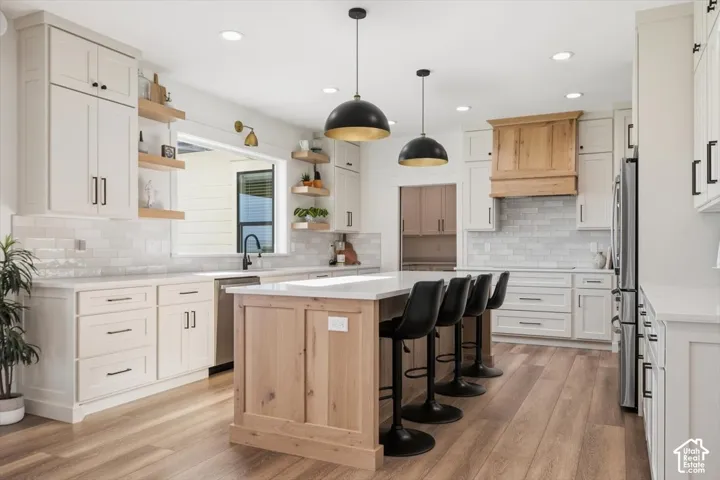 Kitchen featuring light-toned cabinetry, a wood-finished island, white countertops, a subway tile backsplash, and wood-finish flooring