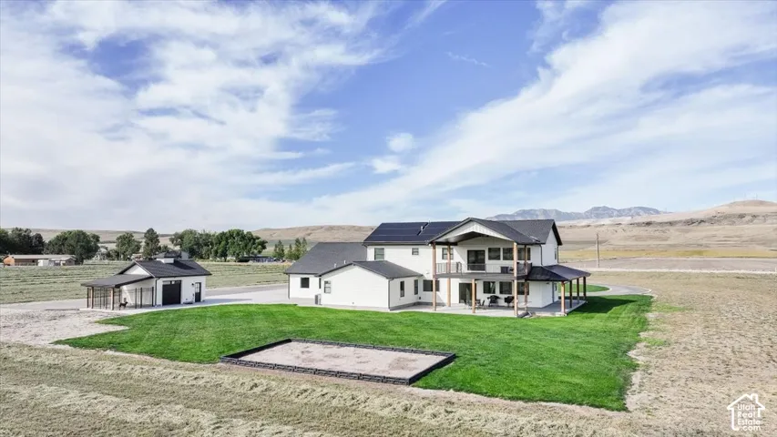 Contemporary residence featuring a two-story design, attached garage, upper-level balcony, and covered patio
