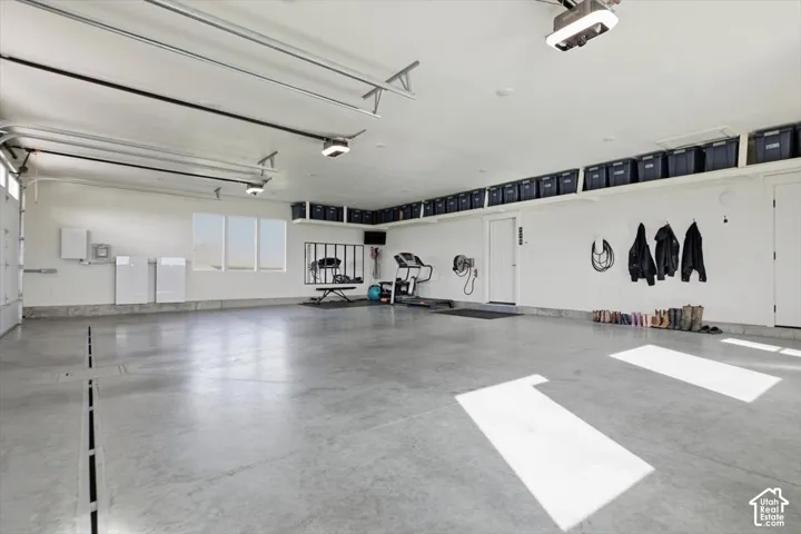 Spacious garage featuring a concrete floor, overhead storage shelving, multiple windows, and recessed lighting