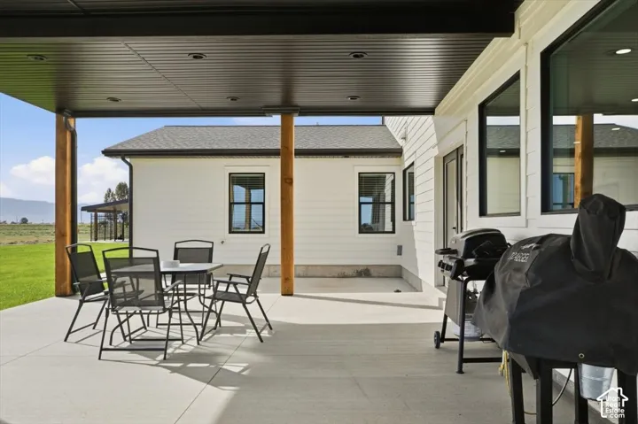 Expansive covered patio featuring a concrete surface, wood columns, and a corrugated ceiling with recessed lighting