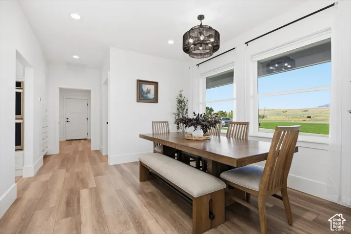 Bright dining area featuring wood-finish flooring, two large windows, and a contemporary chandelier