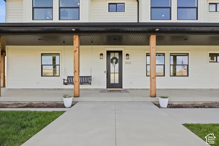 Exterior featuring white siding, black-framed windows, and a covered porch with wood posts
