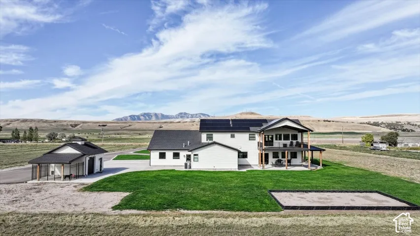 Modern farmhouse exterior with a multi-level deck, ground-level patio, and solar panels