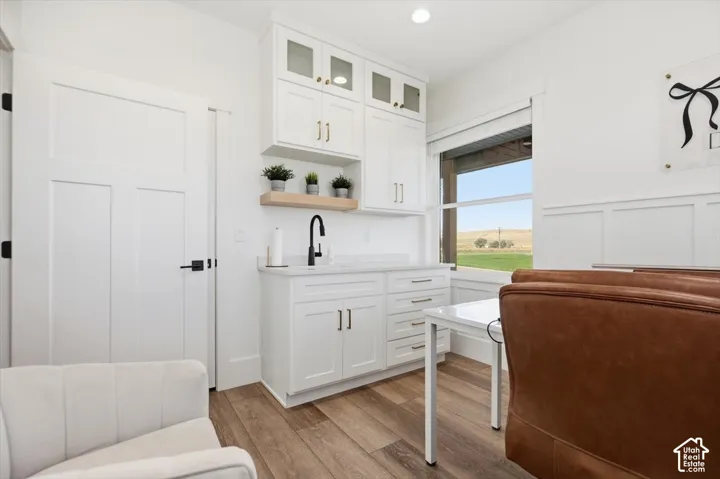 Built-in cabinetry with glass-front uppers, wood-finish flooring, recessed lighting, and a window with exterior scenery