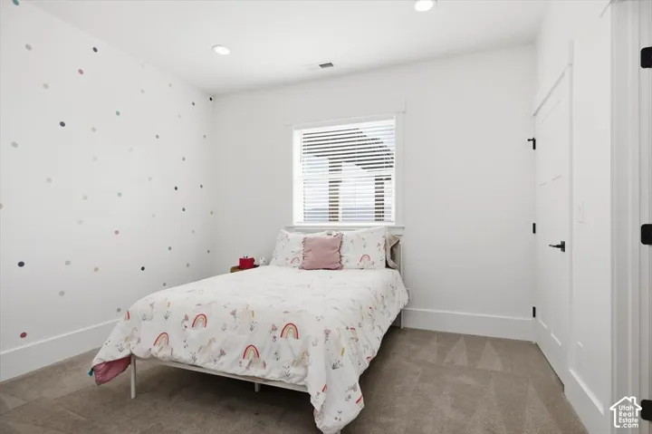 Recessed ceiling lighting, a window with blinds, white trim, a modern paneled door with black hardware, and carpeted flooring