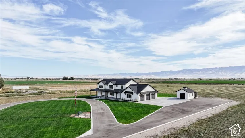 Modern farmhouse-style residence with a covered front porch, attached three-car garage, and a detached outbuilding