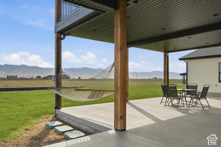 Expansive concrete patio with wood support columns, offering a mountain backdrop and a covered outdoor area