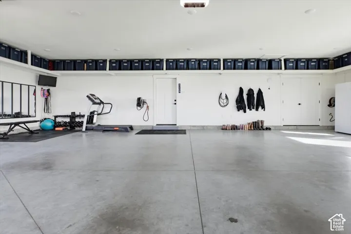 Concrete flooring, white painted walls, overhead recessed lighting, white doors, upper wall shelving