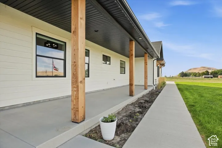 White horizontal siding with black-framed windows, supported by natural wood columns, and a concrete covered porch