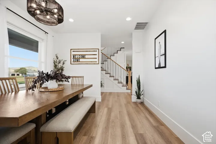 Recessed lighting, wood-finish flooring, staircase with wood handrail, spindle railing, and a large window