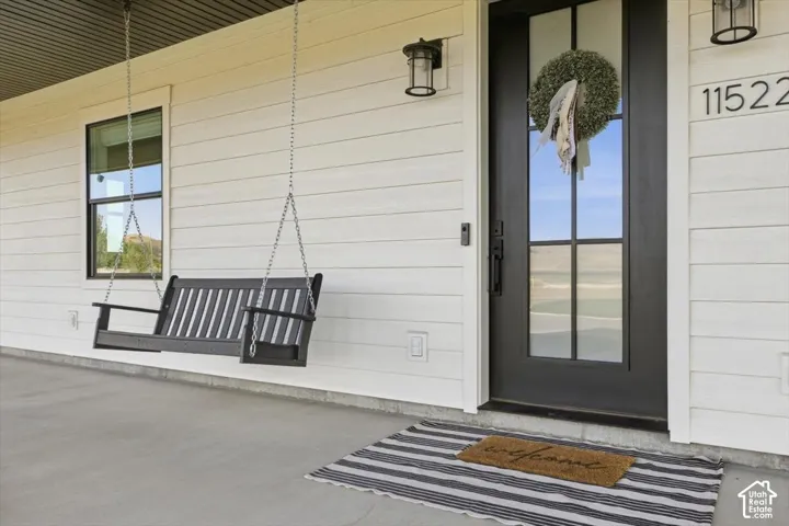 White horizontal siding, black framed window, dark gray front door with glass panels, and exterior sconce lighting