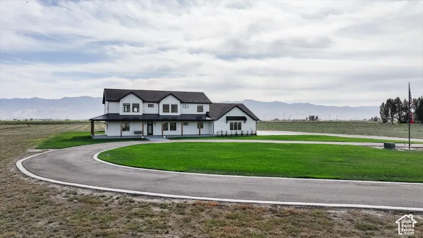 Modern farmhouse architectural style featuring a dark shingle roof, white exterior siding, and a covered porch